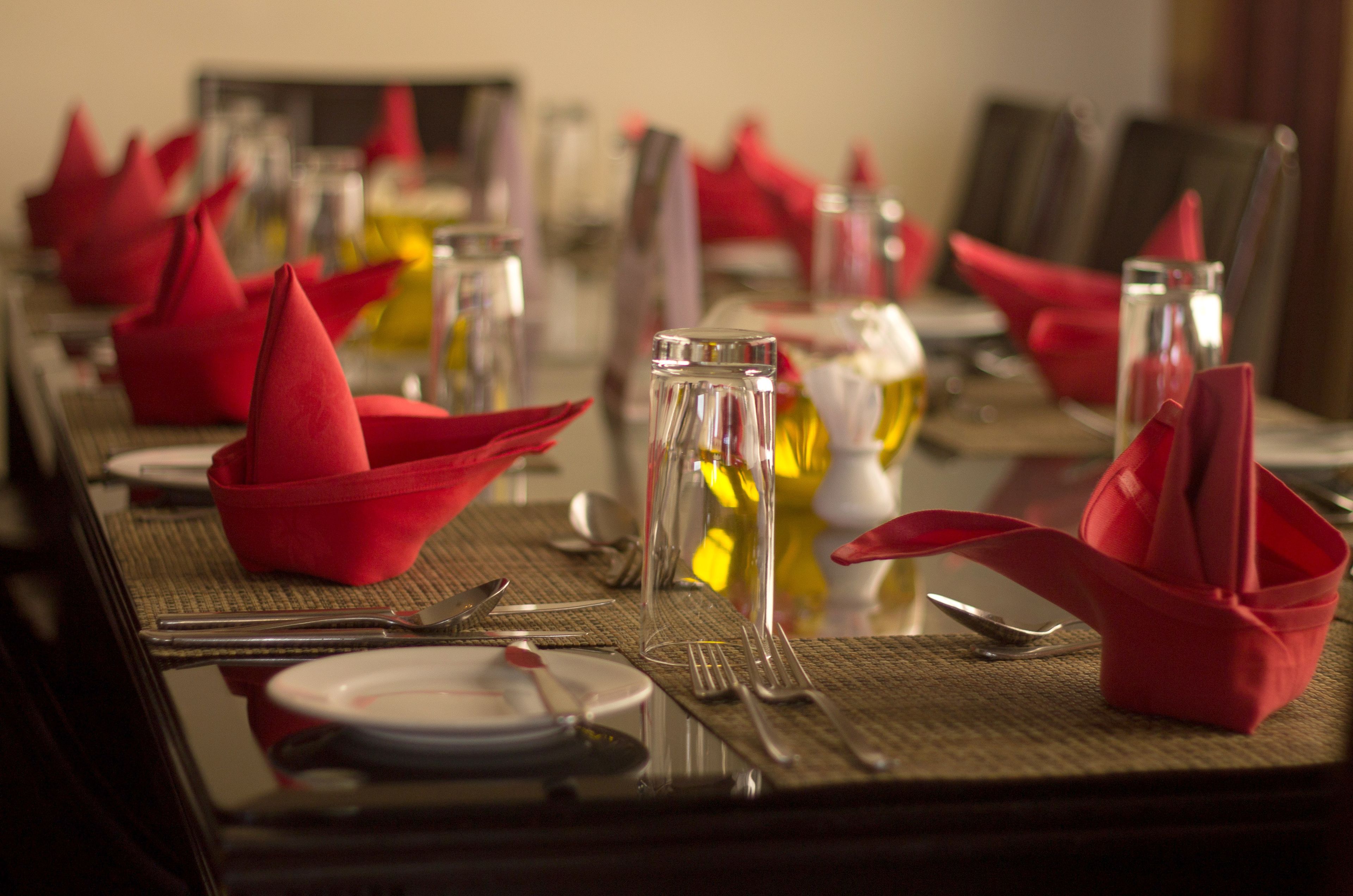 A dining table set with red napkins, clear glassware, and silverware.