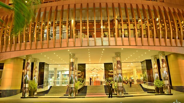 En moderne hotelindgang med en buet facade, store glasfacader og en central trappe til lobbyen.