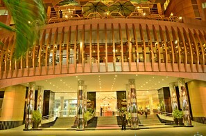 A modern hotel entrance with a curved facade, large glass windows, and a central staircase leading to the lobby. - The Panari Hotel - Near Jomo Kenyatta International Airport (Nairobi)