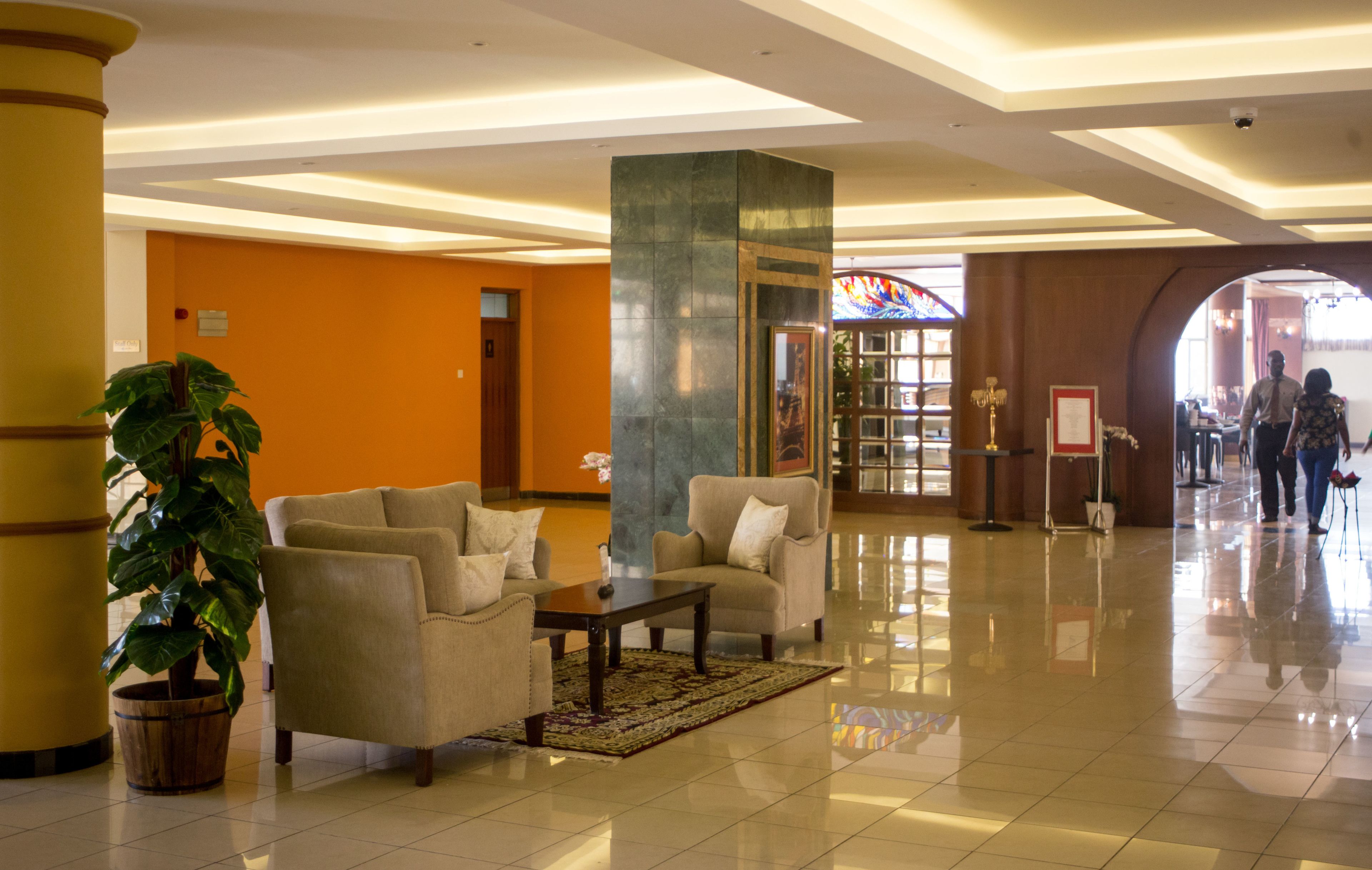 A lobby with a reception desk, seating area, and a large potted plant.