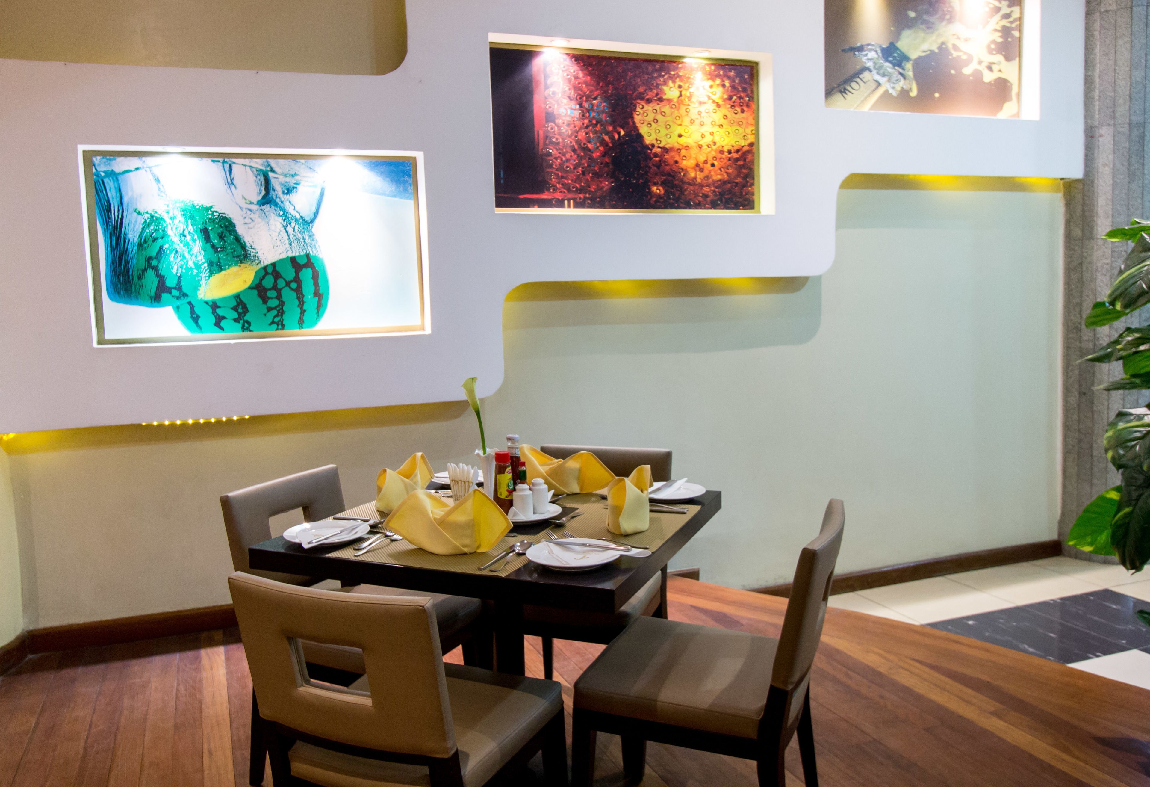 A dining area with a table set for two, chairs, and wall art.