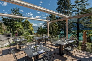 An outdoor dining area with tables and chairs, overlooking a mountainous landscape and a body of water. - Residenza Lago di Lugano (Porlezza)