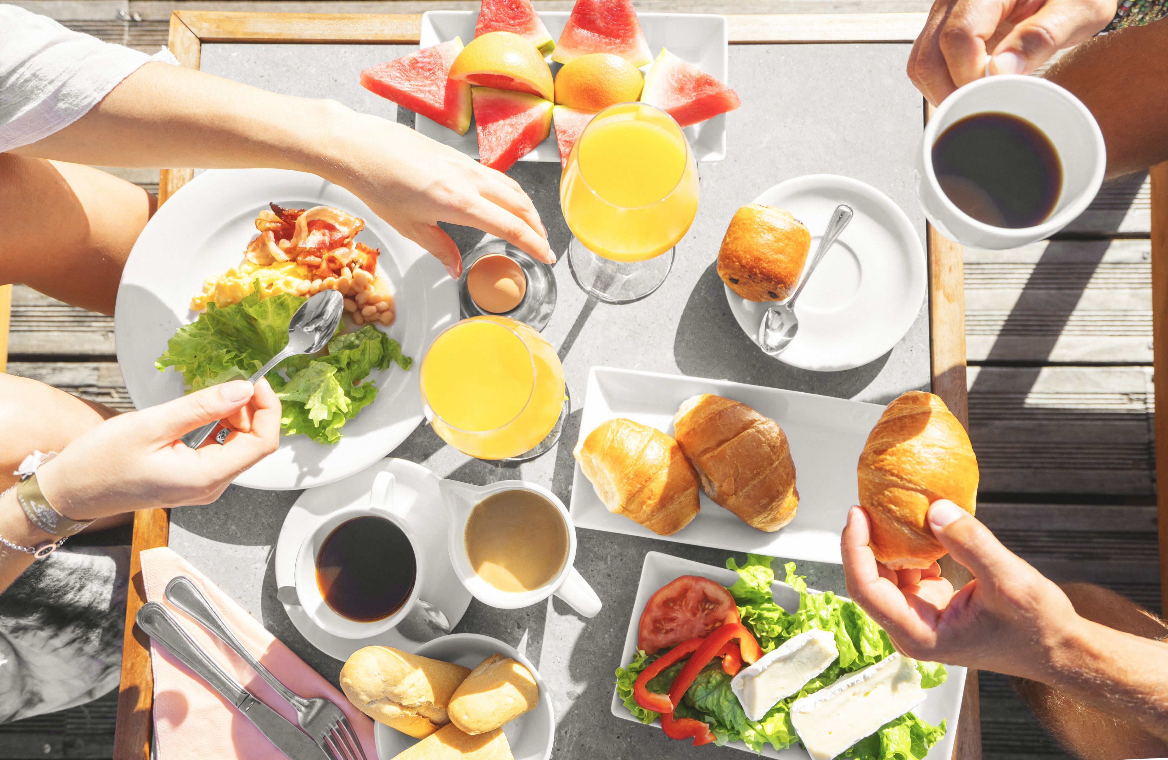 Uma mesa com itens de café da manhã, incluindo croissants, frutas e bebidas.