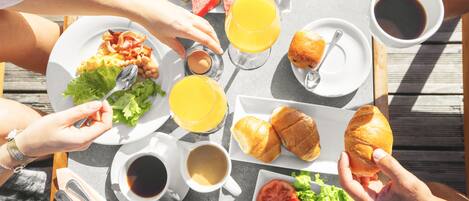 Uma mesa com itens de café da manhã, incluindo croissants, frutas e bebidas.