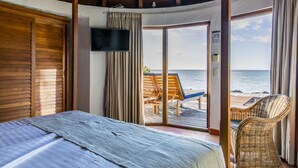 A bedroom with a bed, a TV, and a view of the beach. - Langley Resort Fort Royal (Deshaies)