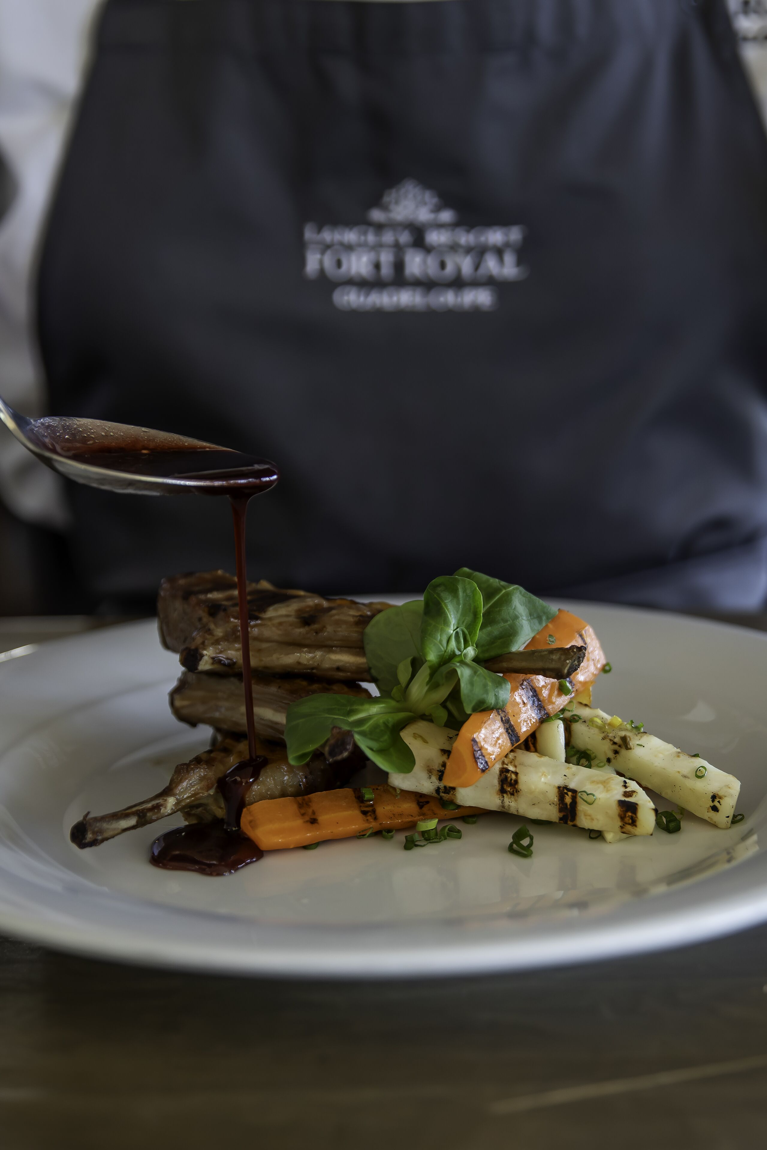 A plate of food with a dark sauce being poured over it.