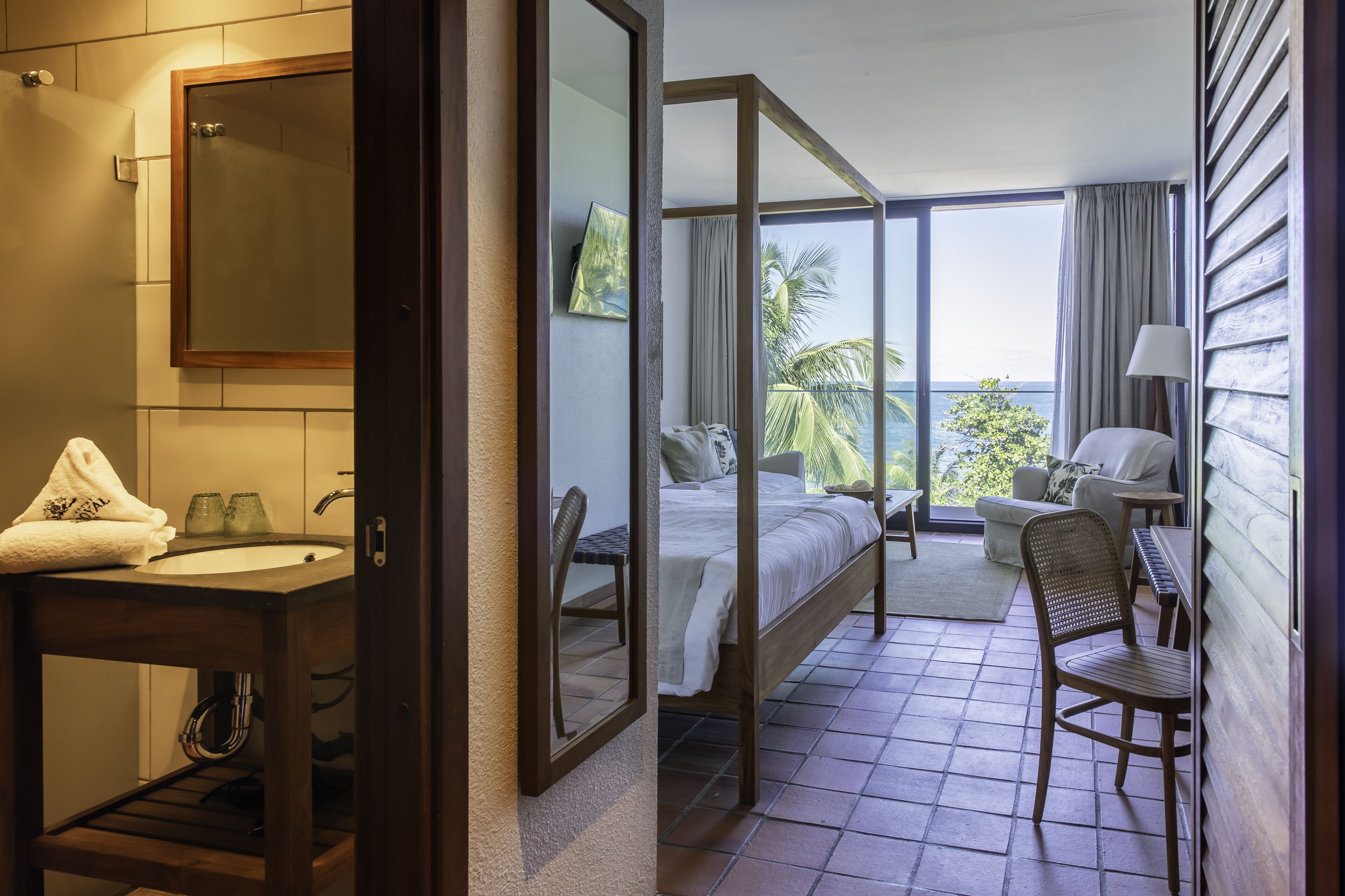 Una habitación de hotel con baño, una cama, una silla y vistas al exterior.