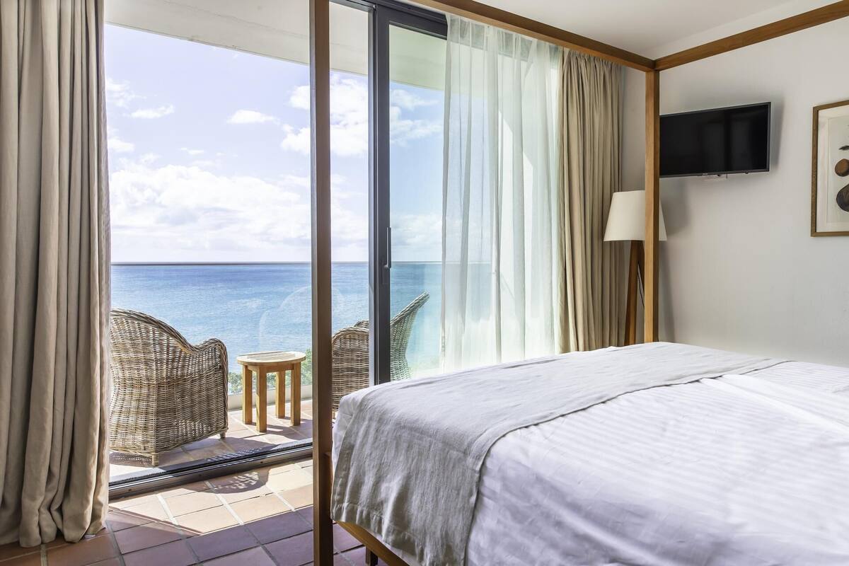 Ein Hotelzimmer mit Bett, Fernseher und Meerblick.