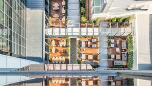 Un edificio moderno con jardín en la azotea, que cuenta con varias zonas de estar y un camino central.