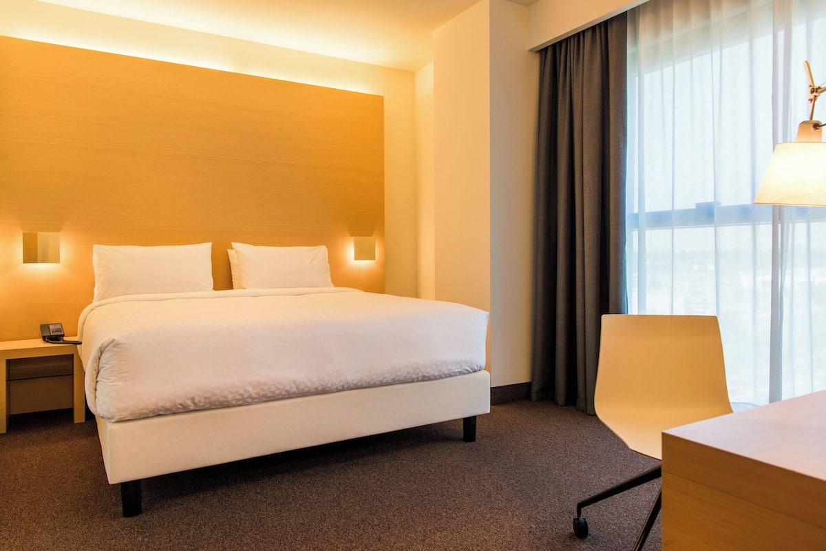 Een hotelkamer met een groot bed, nachtkastjes, een bureau en een stoel.