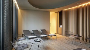 Un área de estar moderna con sillones reclinables, una mesita redonda con bandeja y una pared con listones de madera verticales.