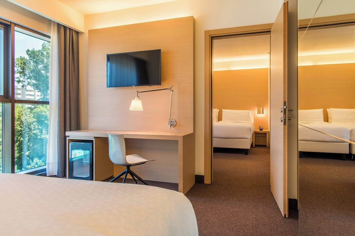 Een hotelkamer met een bed, een bureau met stoel, een televisie en een nachtkastje.