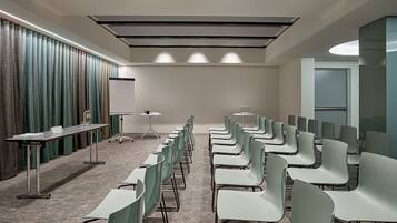 Ein Konferenzraum mit Reihen von Stühlen, einer Tafel und einem Tisch mit Wasserflaschen.