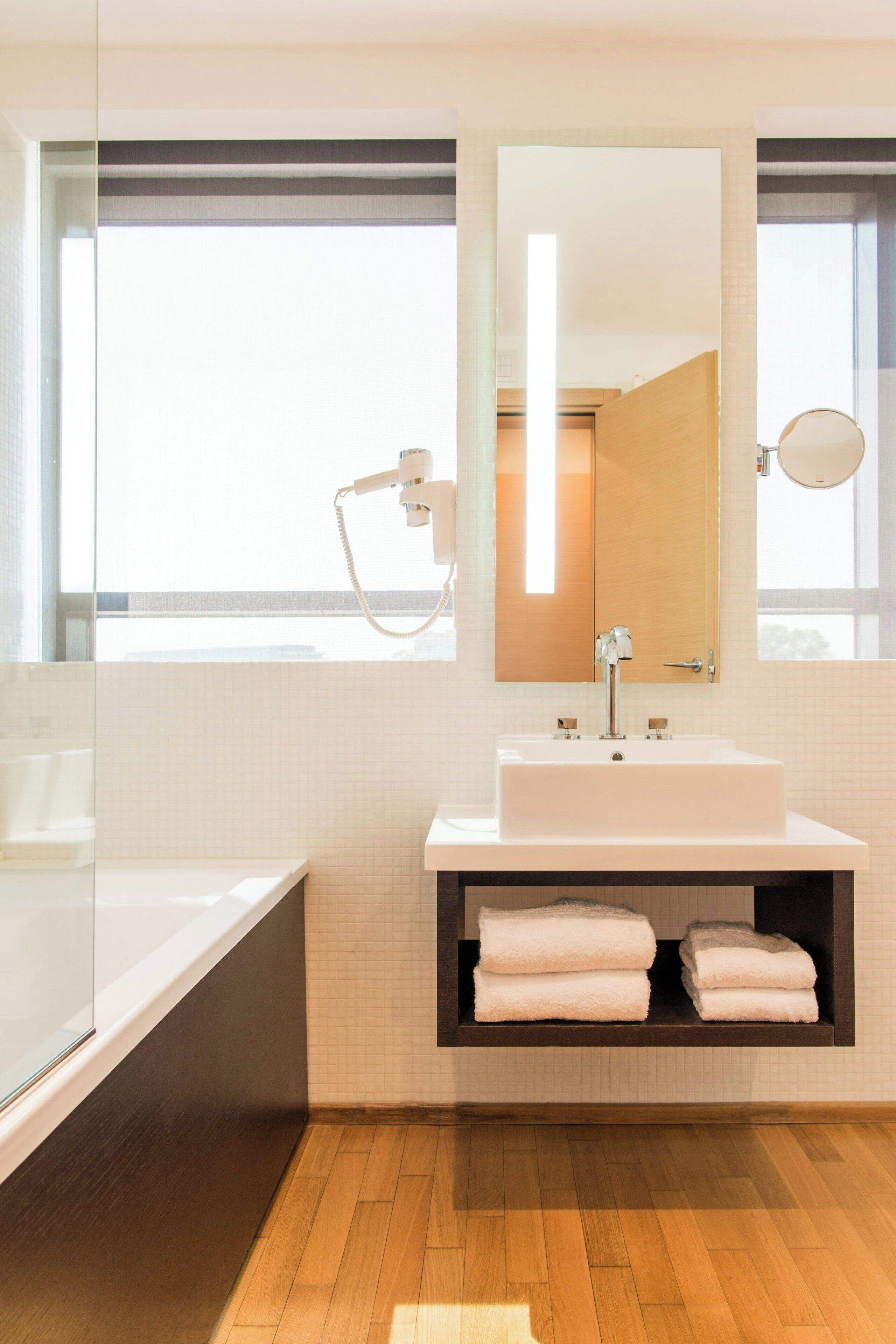 A modern bathroom with a large mirror, a sink, and a towel rack.