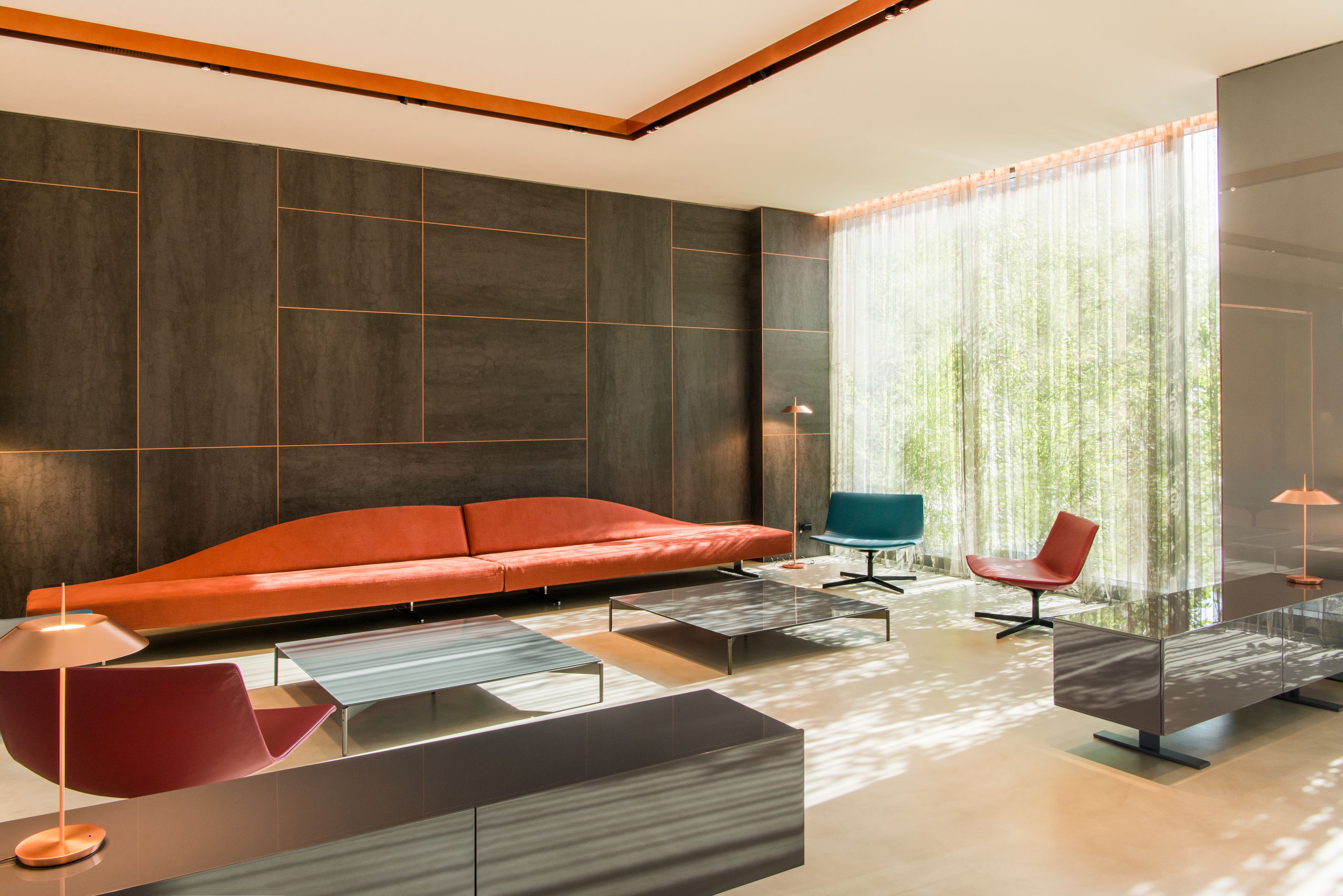 A modern living room with a sectional sofa, a glass coffee table, and a red chair.