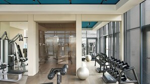 Un gimnasio moderno con equipo de ejercicio, una banca y un espejo grande.