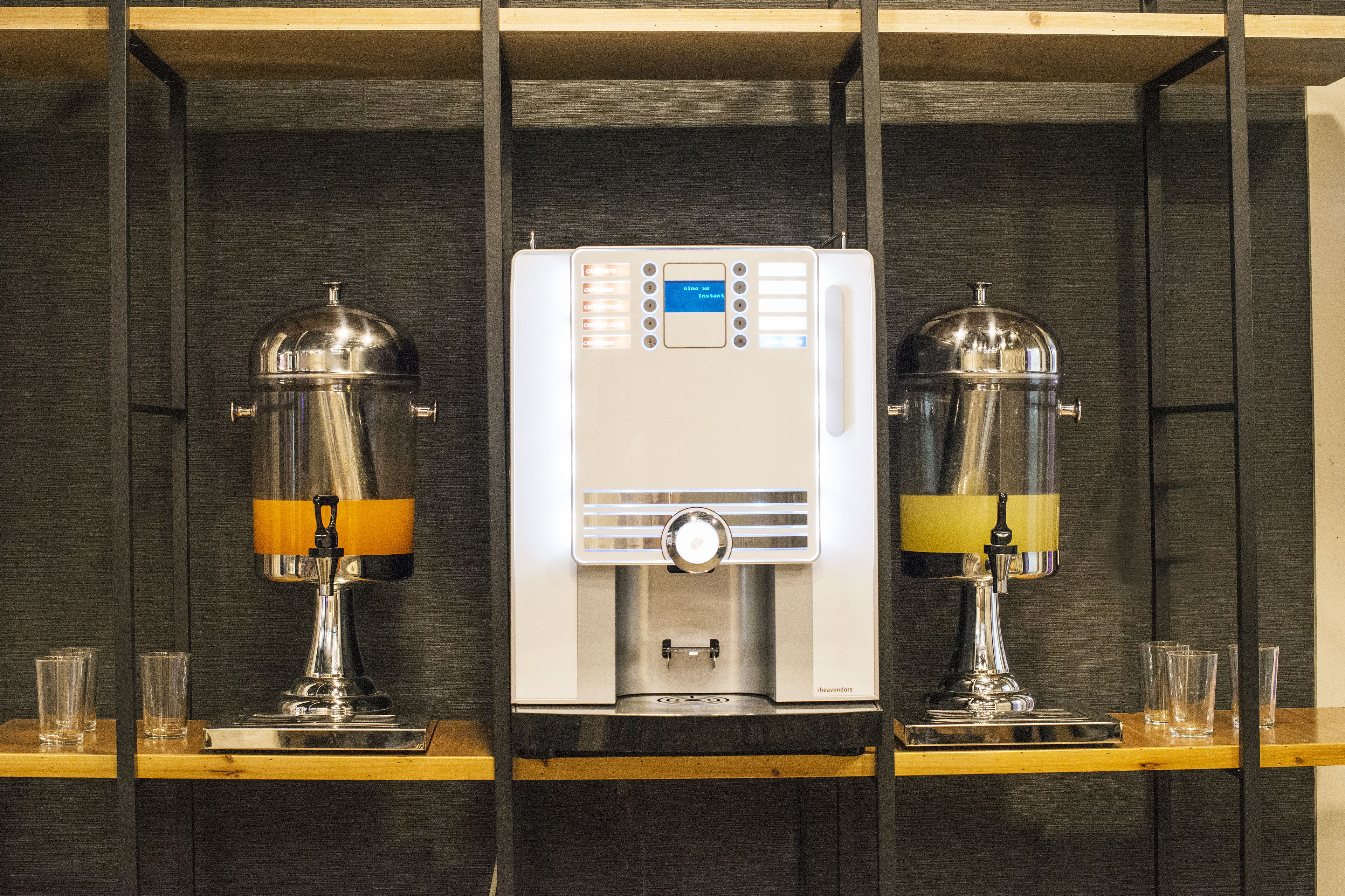 Two espresso machines with control panels, placed on wooden shelves against a dark wall.