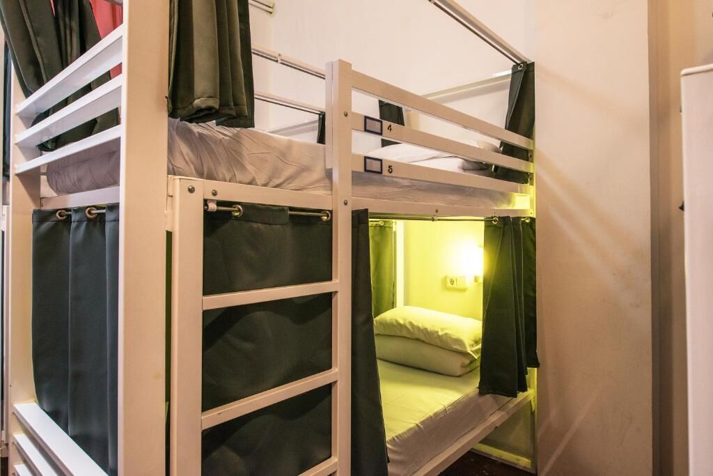 A bunk bed room with a window and a wall-mounted light.