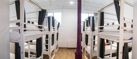 A dormitory room with bunk beds, numbered from 1 to 12, and a central pillar.