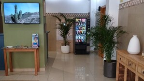 Un hall d’entrée avec un téléviseur, un distributeur automatique et des plantes en pot.