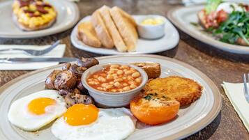 Un plato de desayuno con huevos, frijoles, salchichas y tostadas.