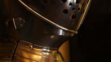 Close-up de um capacete metálico com orifícios de ventilação.