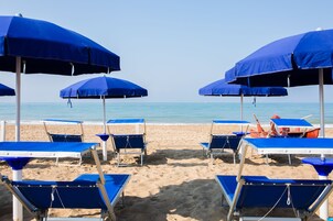 Praia particular, espreguiçadeiras, guarda-sóis, toalhas de praia 