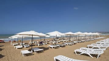 Een privéstrand, ligstoelen aan het strand, parasols, strandlakens