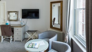 Une chambre d’hôtel équipée d’un bureau, d’une chaise, d’une télévision et d’une grande fenêtre avec des rideaux.