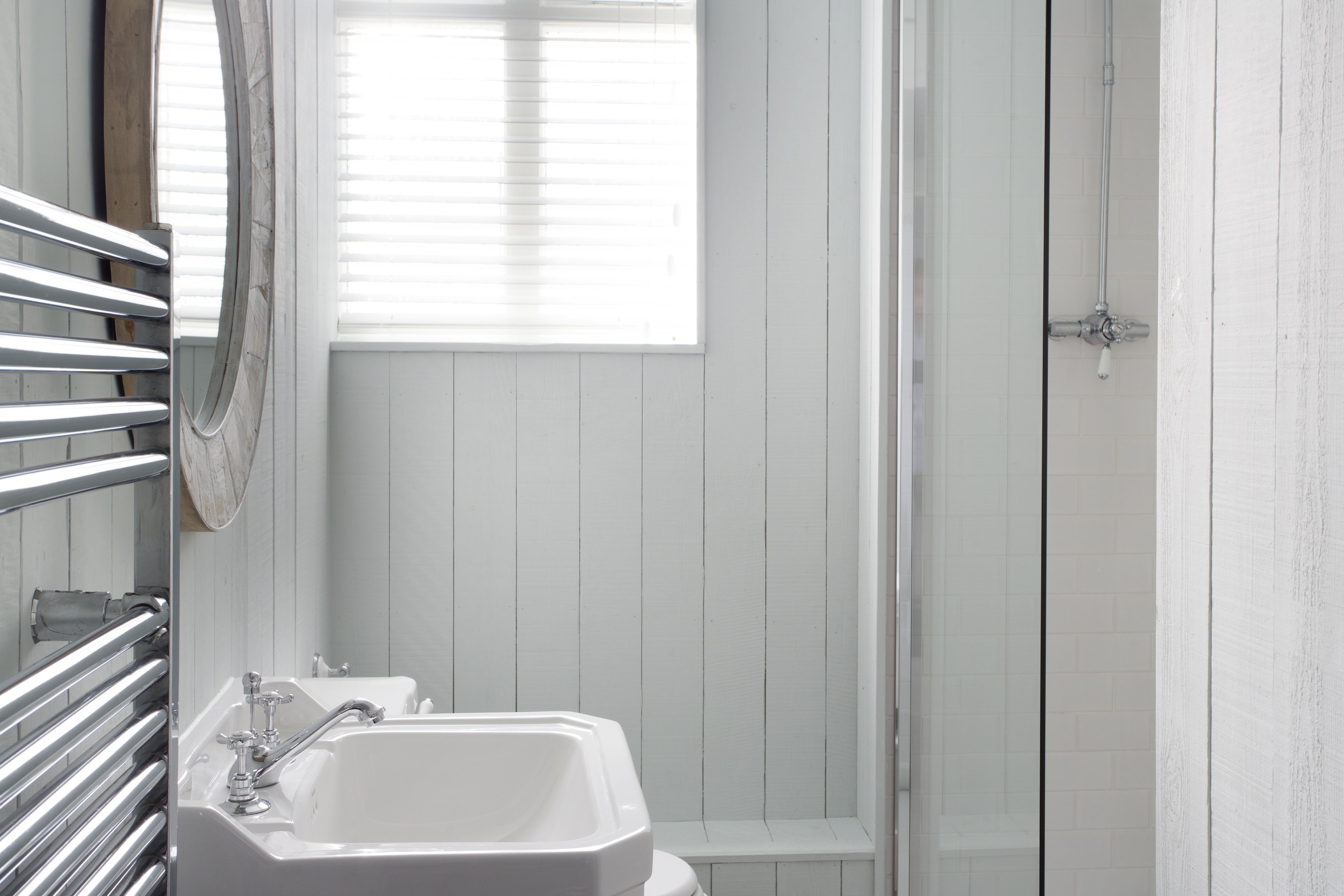 A bathroom with a white sink, a mirror, and a shower area.
