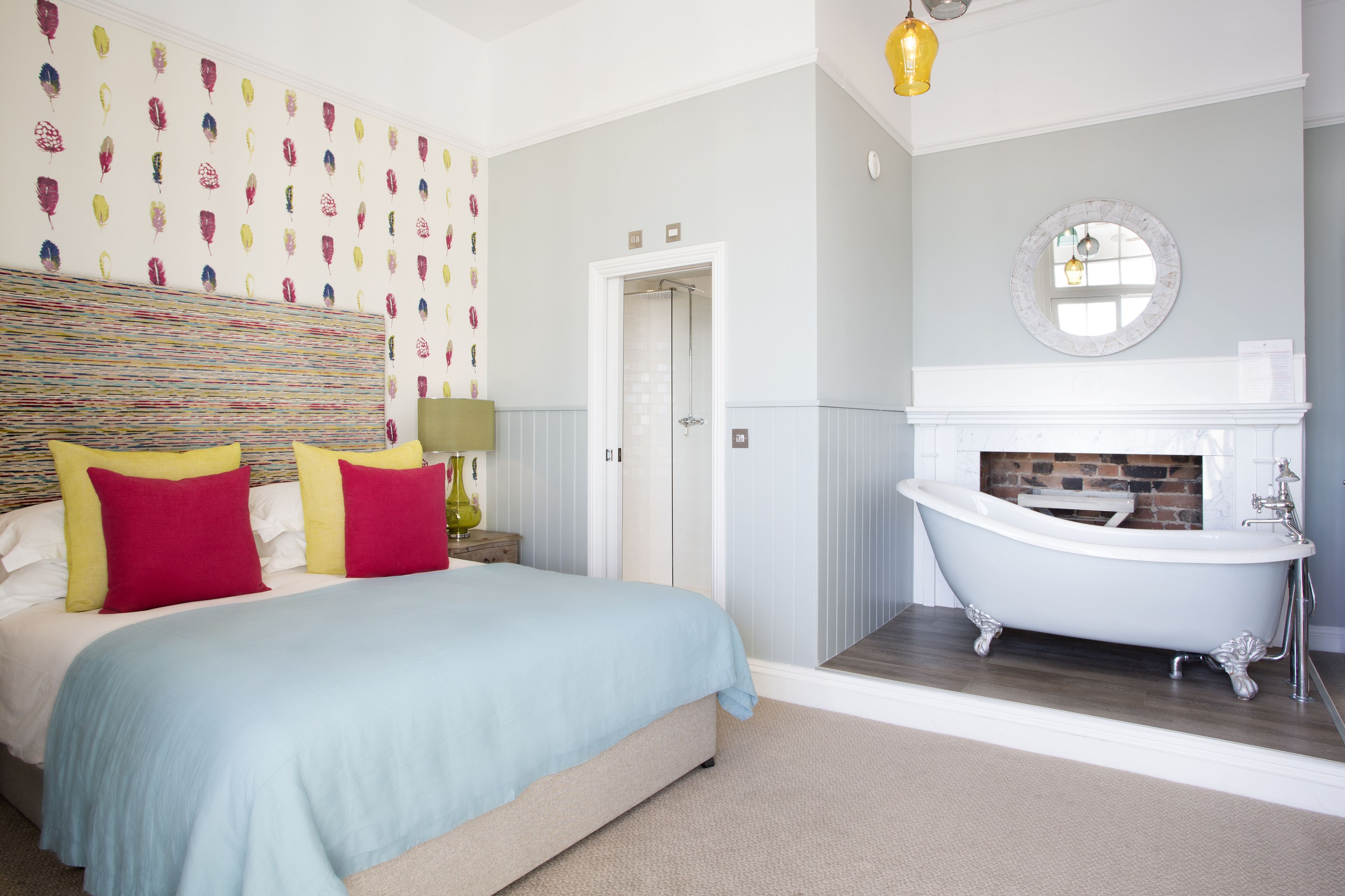 Una camera da letto con un letto, un bagno con una vasca e una parete con un motivo decorativo.