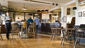 Un espace bar doté d’un plancher en bois, de tabourets de bar et d’un comptoir.