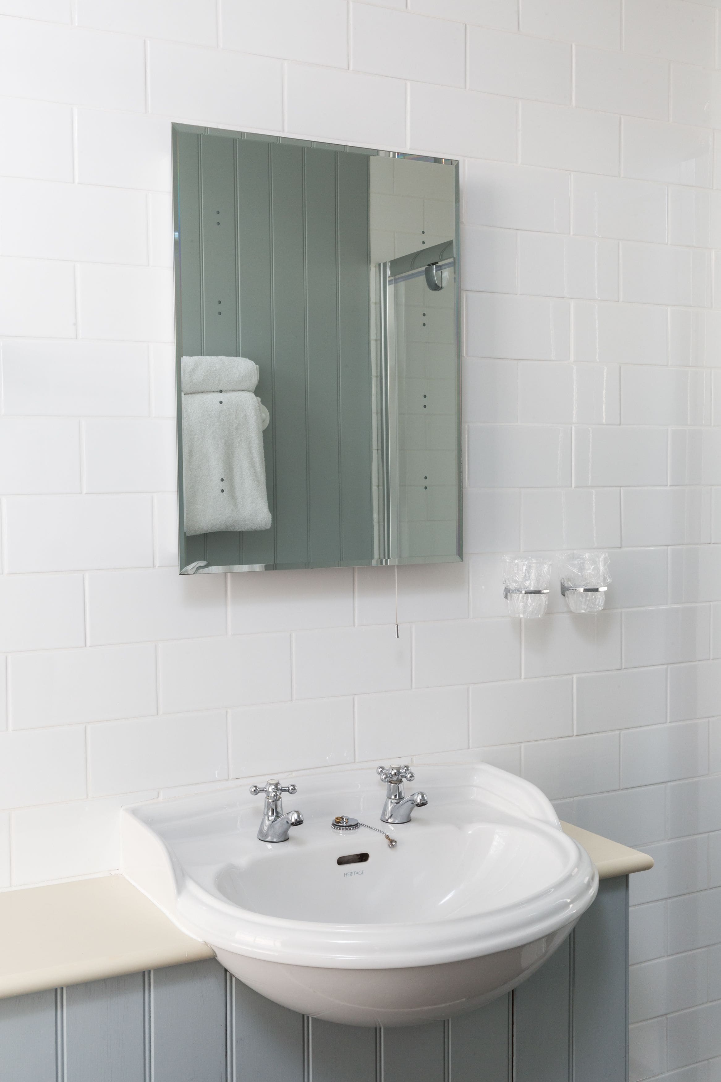 A bathroom with a white sink, a mirror, and a towel rack.