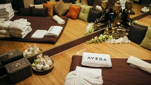 Une chambre d’hôtel bien rangée, avec un grand miroir qui reflète la décoration de la pièce, notamment une statue de Bouddha, des coussins et des serviettes soigneusement pliées.