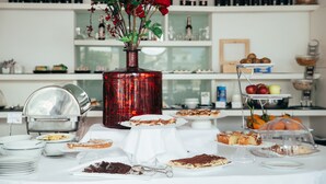 Une table de buffet avec divers desserts et un vase rouge rempli de fleurs.