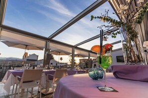 A restaurant terrace with tables set for dining, a clear sky, and a decorative vase with branches and leaves. - Hotel Porta Felice & Spa (Palermo)