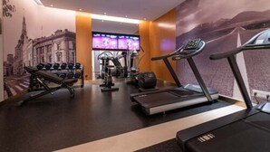 Uma academia com esteiras, halteres e aparelhos de ginástica.