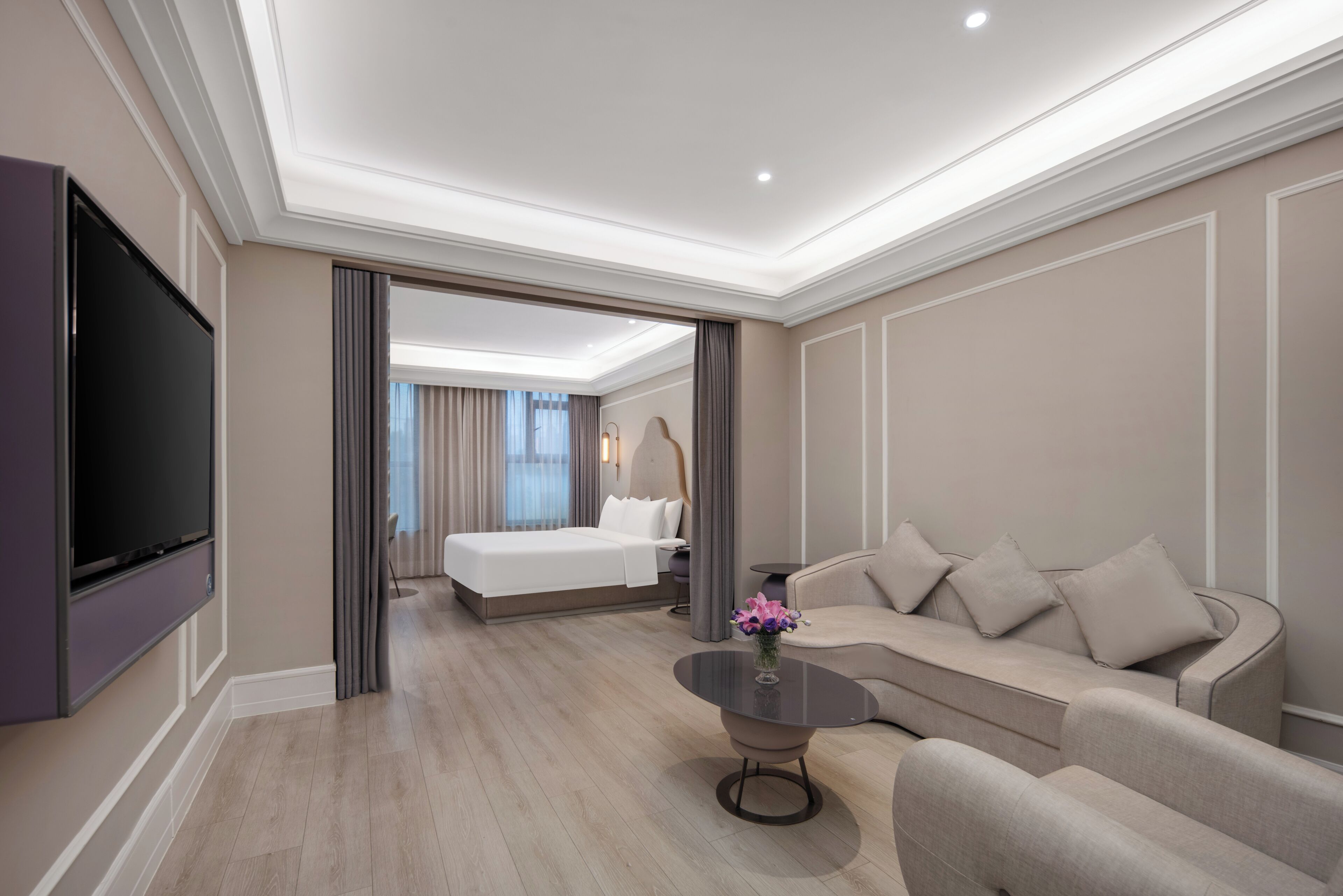 Ein modernes Hotelzimmer mit Fernseher, einer Couch, einem Couchtisch und einem Bett mit Blick.