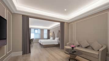 A hotel room with a bed, a sofa, a TV, and a dining area.