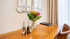 A wooden table with three champagne flutes, a vase with flowers, and a mirror on the wall. - Hotel Europa (Brno)