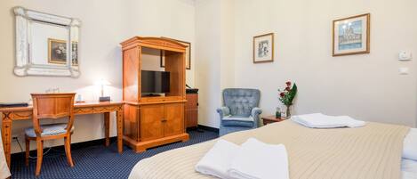 Una habitación de hotel con cama, escritorio, silla, armario y televisión.