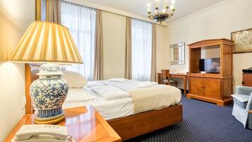A hotel room with a bed, bedside lamp, telephone, desk, television, and a cabinet.