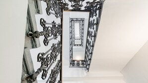 A staircase with ornate black metal railings and a mirrored wall reflecting the interior. - Hotel Europa (Brno)