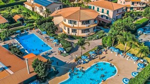 Ein Resort mit mehreren Swimmingpools, Liegestühlen und Palmen.
