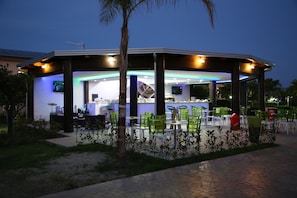 Un restaurant en plein air doté d’un espace repas couvert, de tables et de chaises.