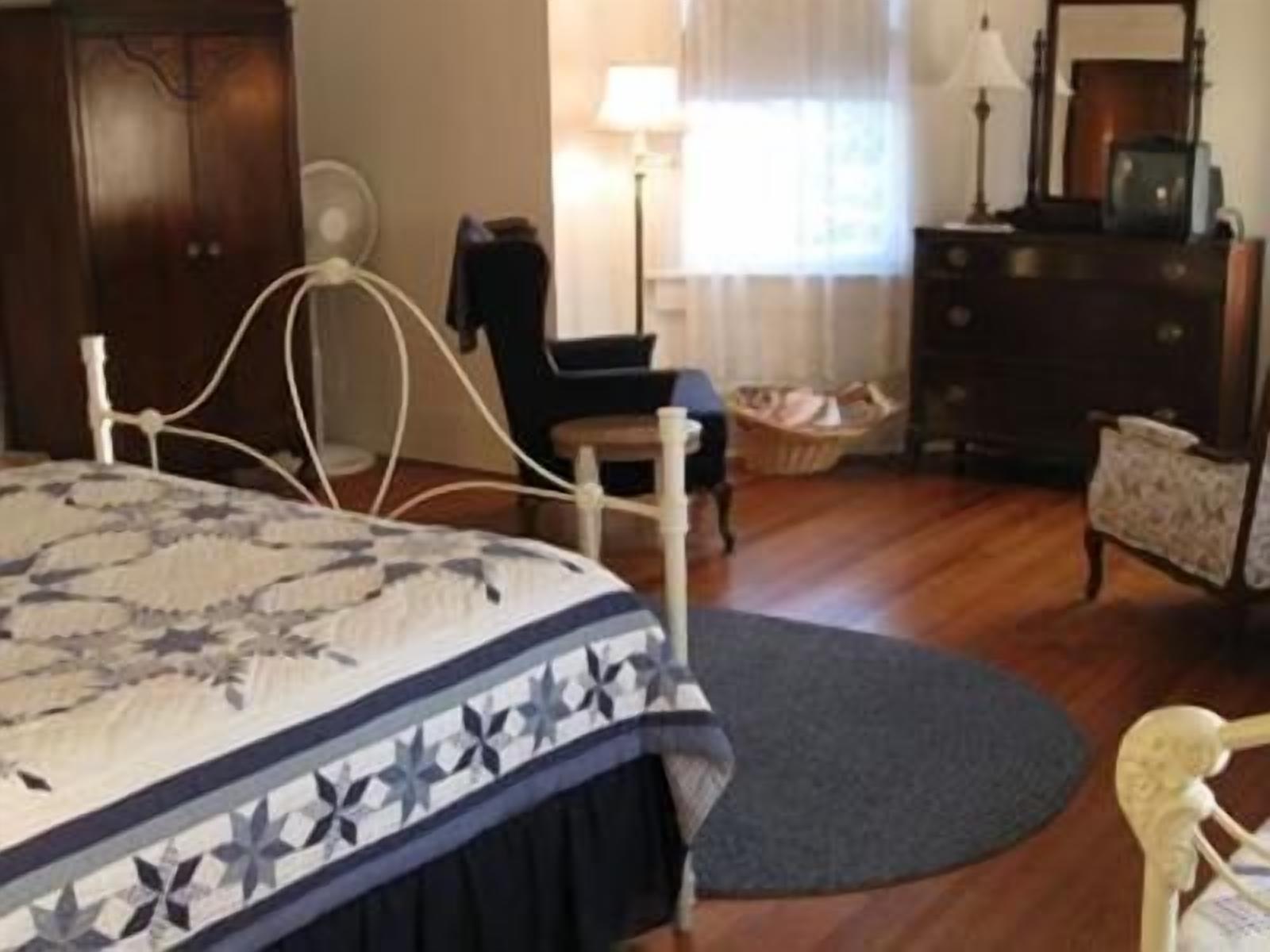A bedroom with a bed, dresser, chair, and lamp.