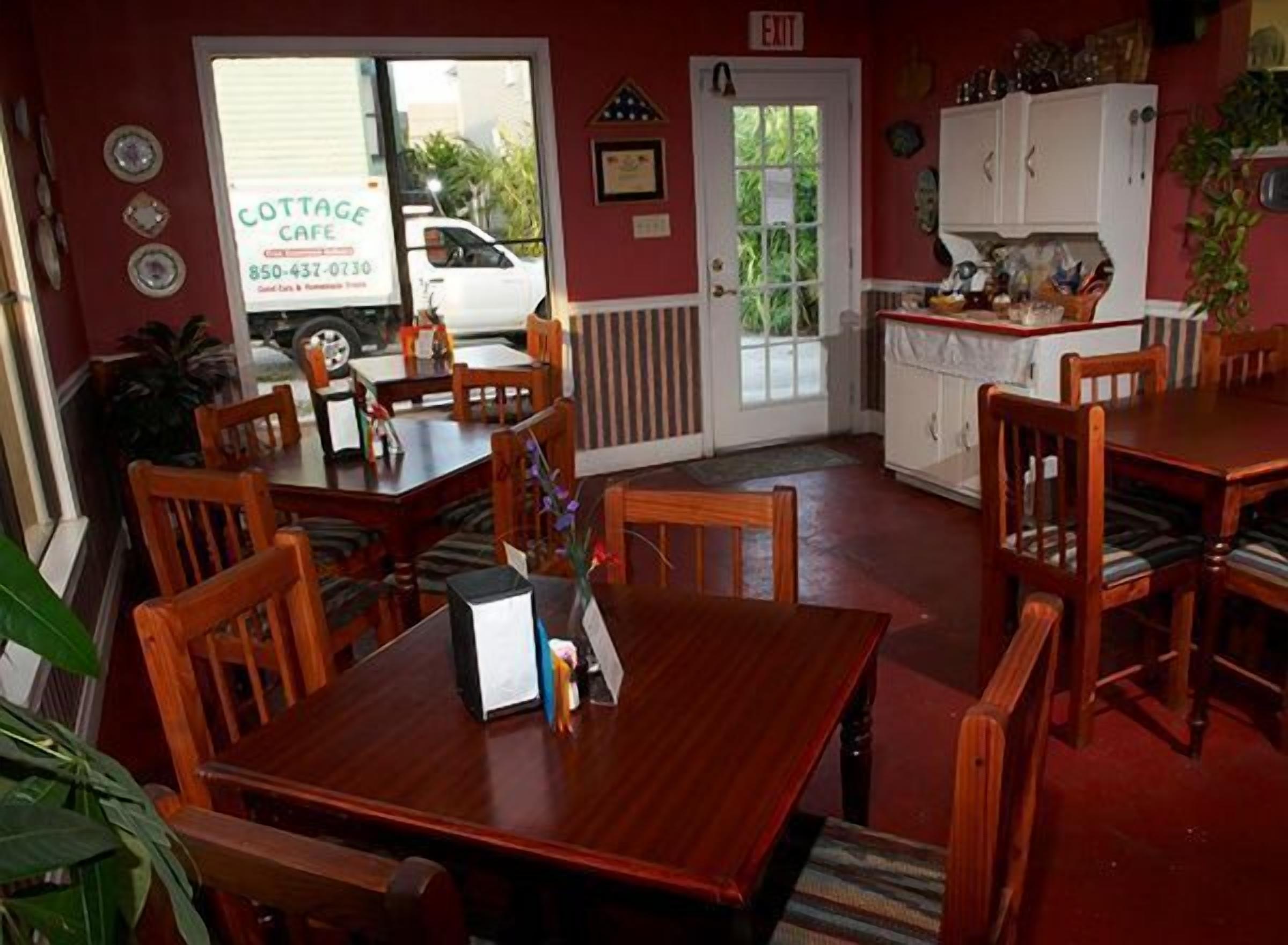 Un restaurant chaleureux avec des tables et des chaises en bois, un comptoir blanc et une porte donnant sur l’extérieur.