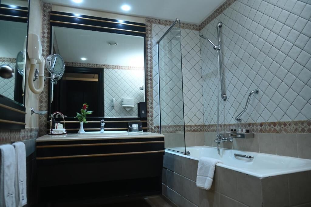 Une salle de bain moderne avec un grand miroir, deux lavabos, une baignoire et une douche à l’italienne.
