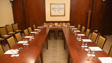 Une salle de conférence avec une longue table en bois, plusieurs chaises et un tableau accroché au mur.
