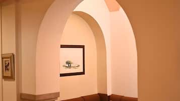 A dining area with a table set for two, a cushioned bench, and a framed artwork on the wall.